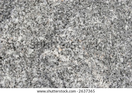 A smooth surface of granite with various speckles of grey, black, silver and white.