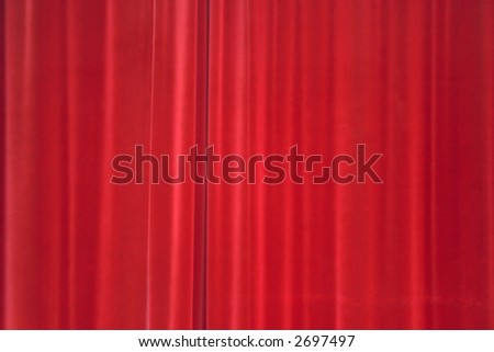 Velvety red curtains in front of a theater stage.