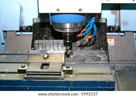 A computerized machine making precision cuts in metal pieces while the work is being constantly irrigated with water to reduce heat.