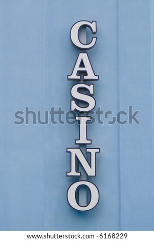 A vertical unlit neon Casino sign on a rough textured wall.