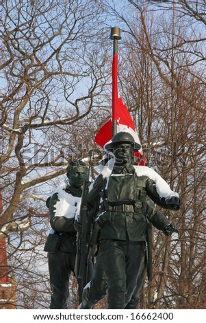 Snow covered war memorial of World War 1 soldiers with a Canadian Flag in the background.  Located in Charlottetown, Prince Edward Island, Canada.