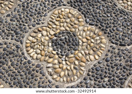 Flower pattern of pebbles in the hard surface paving of a Japanese garden.