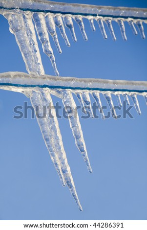 Long icicles hanging off the cloths line against a bright blue sky.