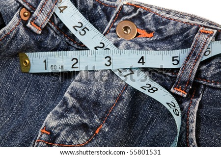Using a measuring tape to measure the waist of a pair of jeans.