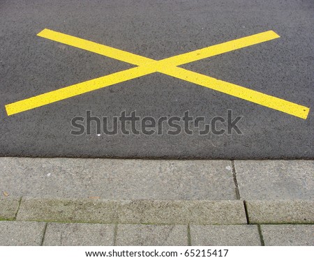 sidewalk with bright yellow paint cross on road
