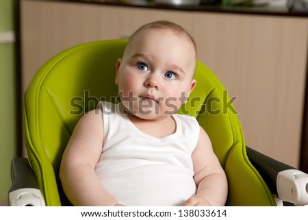 Eight month old baby sitting in a special chair for feeding