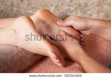 Masseur doing massage on a feet for a young girl on a massage table