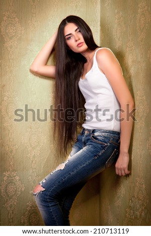 Portrait of young beautiful girl with long hair near the wall in the corner