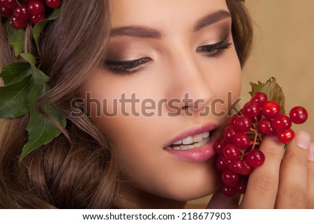 Creative makeup. Young beautiful girl with make-up with a berry and a leaf on yellow background.