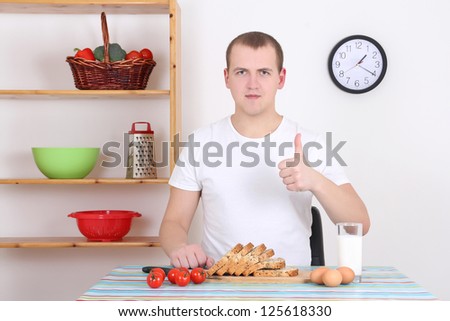 young attractive man thumbs up in the kitchen