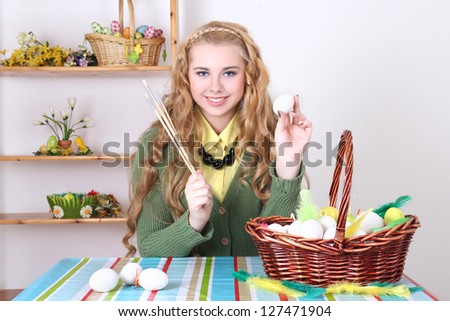 attractive teenage girl with long curly hair painting easter eggs