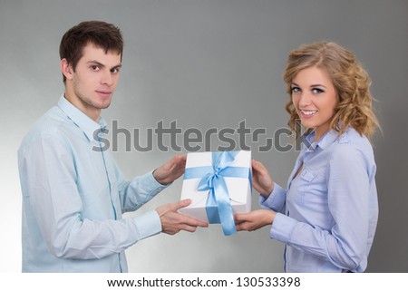 young man giving a gift to his beautiful girlfriend over grey