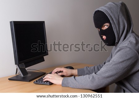 young masked hacker using a computer