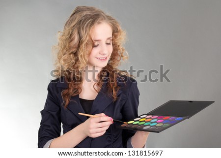 young beautiful woman with make up brushes and palette over grey