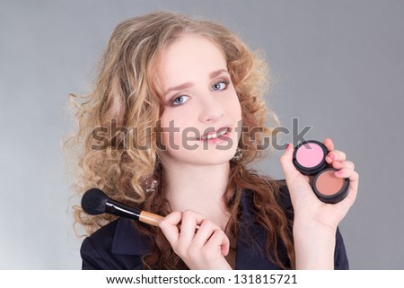 young attractive make up artist with brush over grey
