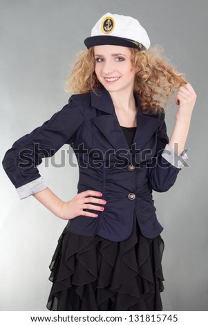 young beautiful woman in captain cap over grey background