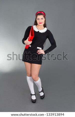 young sexy teacher with red folder over grey background