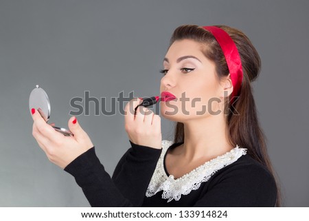 pinup woman with little mirror putting red lipstick