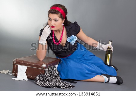 drunk pinup girl with bottle of champagne and packed suitcase