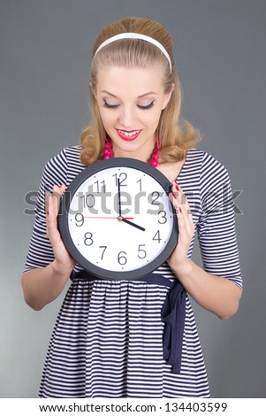 dreaming pinup girl in striped dress with clock over grey background