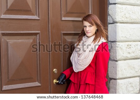 young beautiful redhaired woman in front of the old door