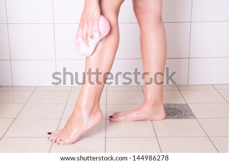 woman washing her legs with sponge in shower