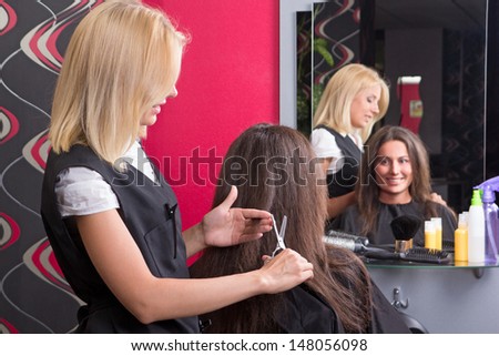 female hairdresser makes hairstyle for beautiful girl in beauty salon