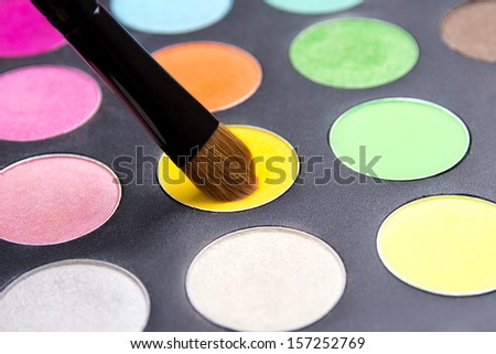 close up of Make-up brush and colorful eyeshadow palette over black background
