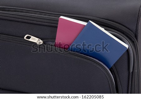 close up of black travel suitcase and two passports