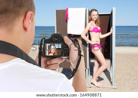 slim beautiful woman in changing cabin and photographer on the beach