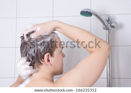 back view of young attractive man washing hair in shower
