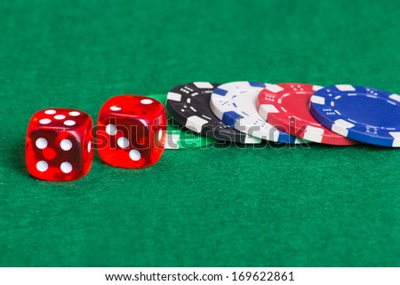 colorful poker chips and dice on a green casino felt