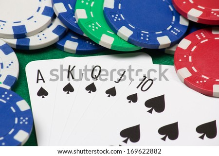 royal flush combination and playing poker chips on the green casino table