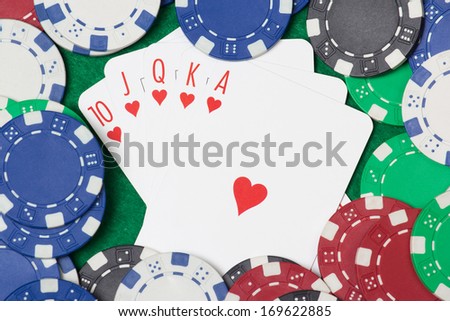 Poker cards with royal flush combination and chips on green casino table