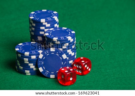 heap of blue poker chips and red cubes on the green table
