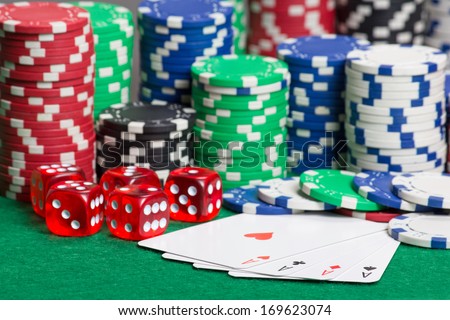 dice, four aces and colorful poker chips on a green table