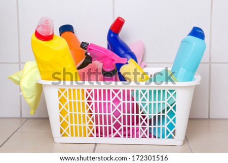 cleaning supplies in plastic box on tiled floor in bathroom