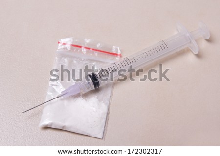 drug syringe and heroin powder in pack on tiled floor