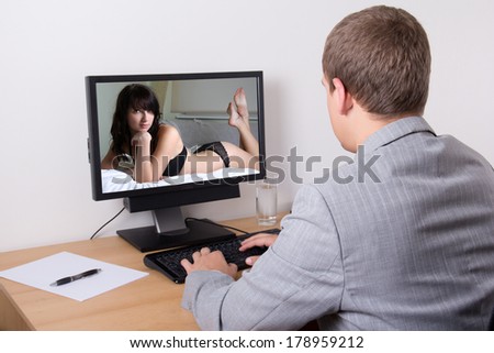 back view of young businessman looking at sexy woman in computer at work