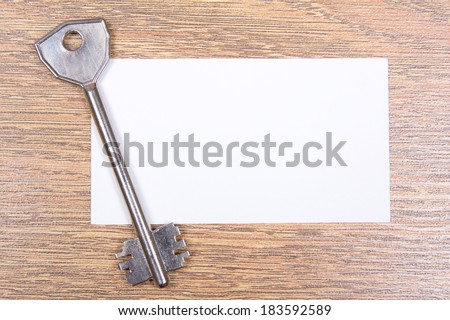 metal key and visiting card on wooden desktop