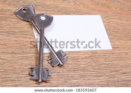 close up of two metal keys and visiting card on wooden table