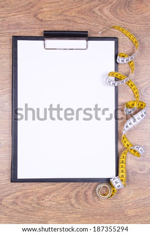 blank clipboard and measure tape on wooden table