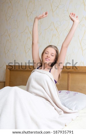happy young woman waking up and stretching her arms up