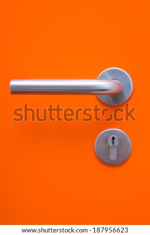 the part of orange door with metal handle and keyhole