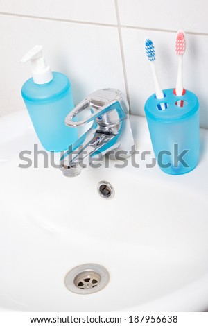 close up of tooth brushes and soap on white sink
