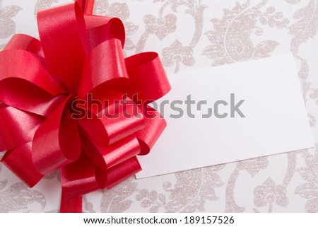 close up of gift box with big red bow and empty greeting card