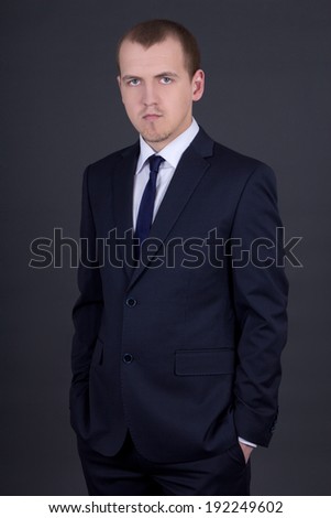 young business man in suit over grey background