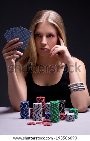 young beautiful serious woman playing poker in casino
