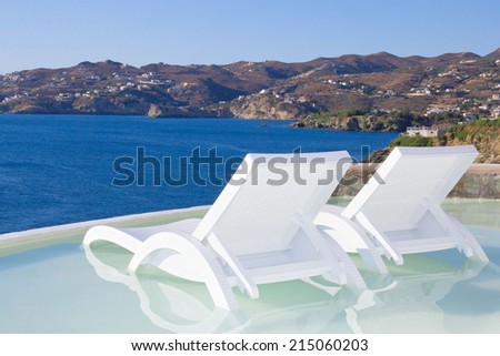 two white beach chairs in pool with beautiful sea view in Greece