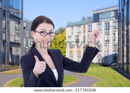 female real estate agent with key standing on street against modern building